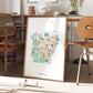 a framed illustration of a map of Arkansas, with various landmarks and symbols representing different regions within the state.