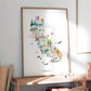 The image is a framed poster of a colorful illustration depicting various landmarks and scenes from California, including the Golden Gate Bridge, palm trees, hot air balloons, and other iconic symbols.