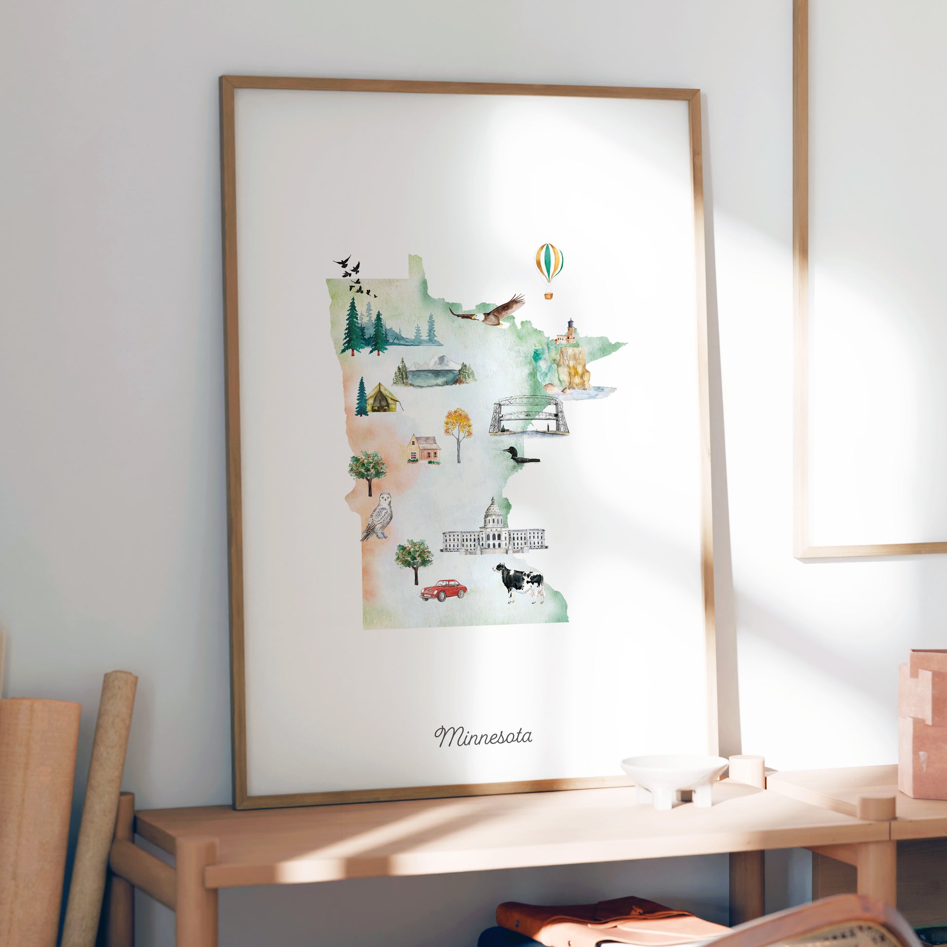 a framed watercolor illustration of Minnesota, depicting various landmarks and scenes from the state.