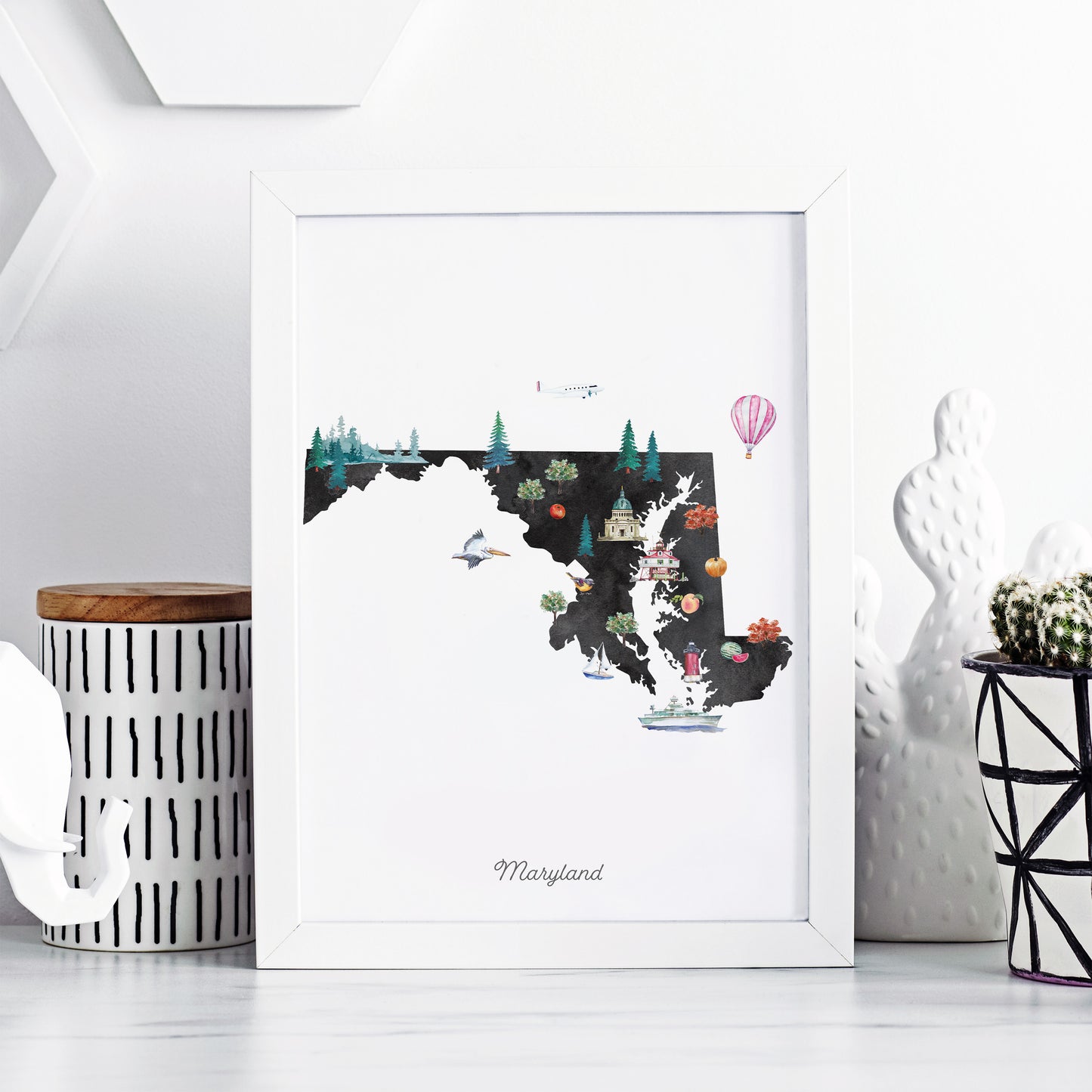A framed illustration of the state of Maryland, featuring various landmarks and elements such as a hot air balloon, cacti, and a bird.