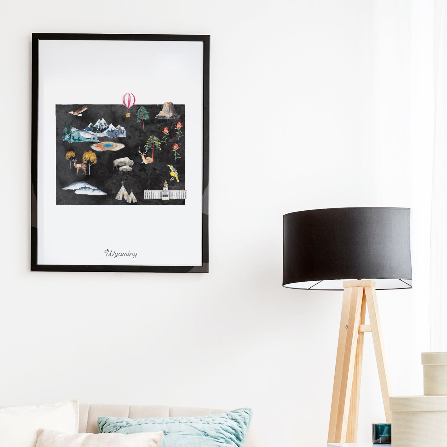 a framed artwork depicting various scenes and objects, including mountains, a hot air balloon, and a bird, hanging on a wall above a wooden floor lamp.