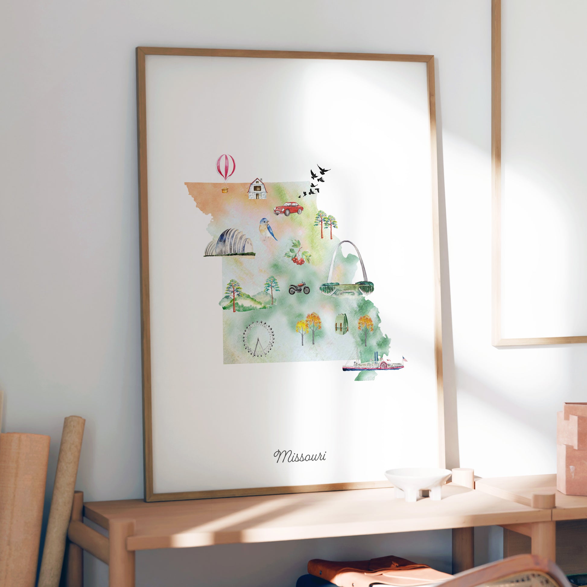 a framed watercolor painting of a map of Missouri, with various landmarks and symbols depicted.