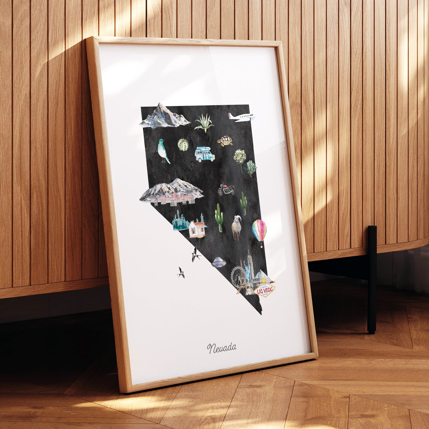 The image is a framed poster depicting various scenes and landmarks of Nevada, including mountains, hot air balloons, and a Las Vegas sign.