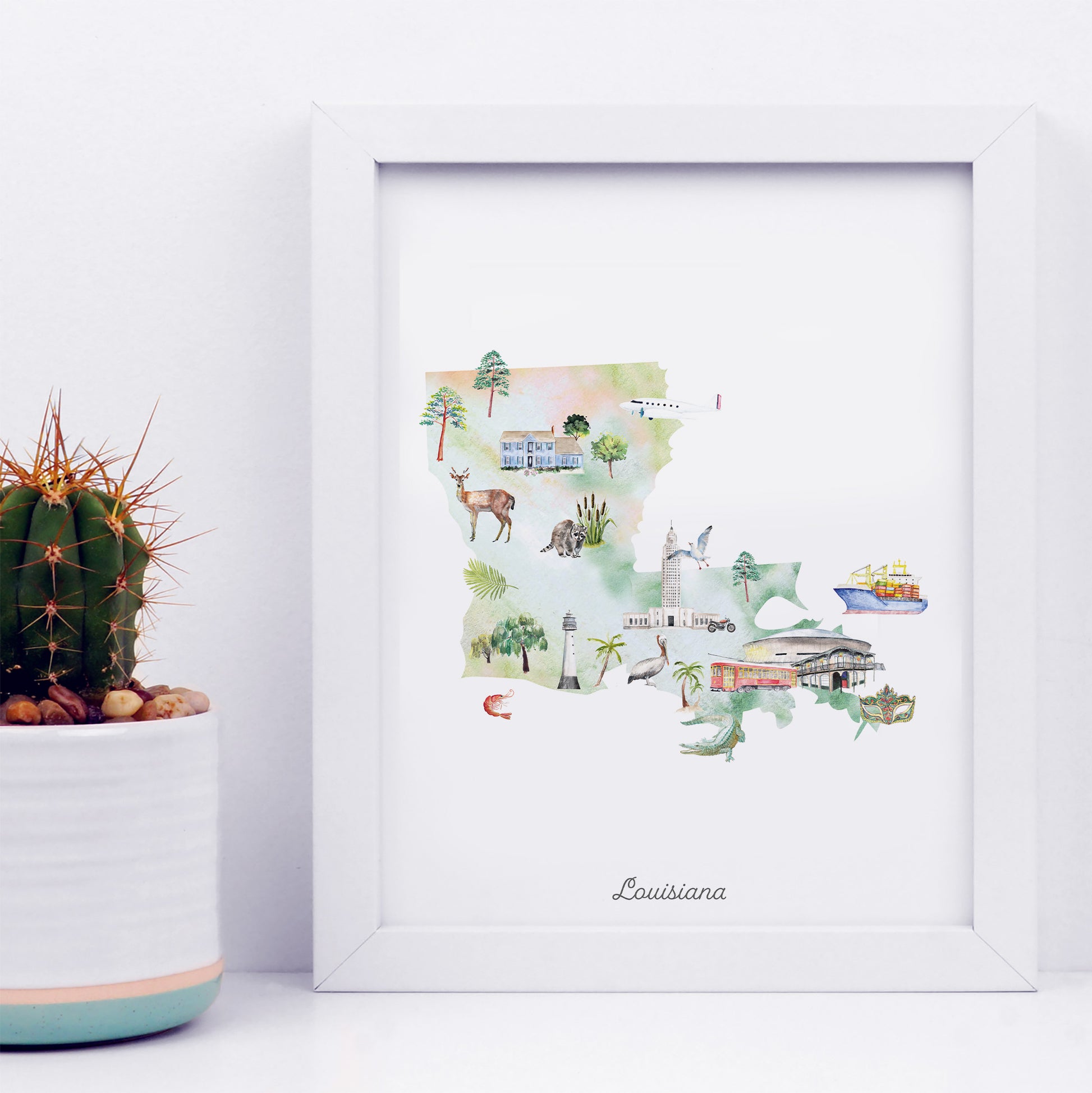 A framed watercolor illustration depicting various landmarks and scenes from Louisiana, including a cactus, a deer, a building, and a boat.