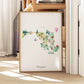 A framed watercolor illustration of a map of Maryland, featuring various landmarks and symbols.
