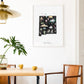 a dining area with a wooden table, two yellow mugs, and a framed poster of New Mexico hanging on the wall.