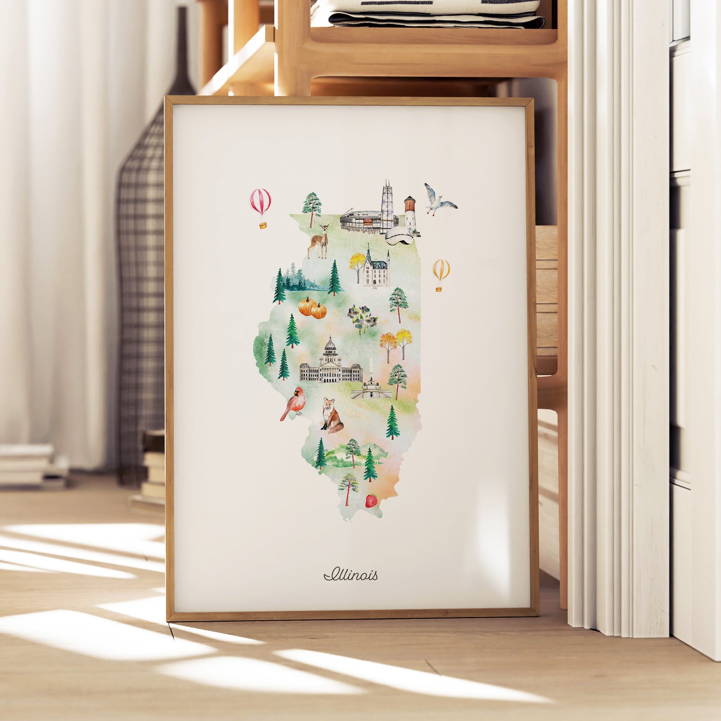 A framed watercolor illustration depicting various landmarks and scenes from Illinois, including a hot air balloon, a church, and a forest.